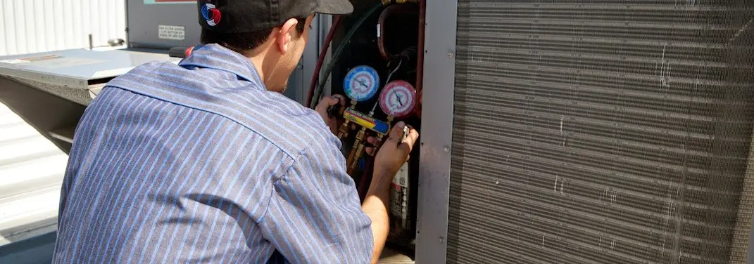 HVAC technician servicing a condenser unit in Woodmere