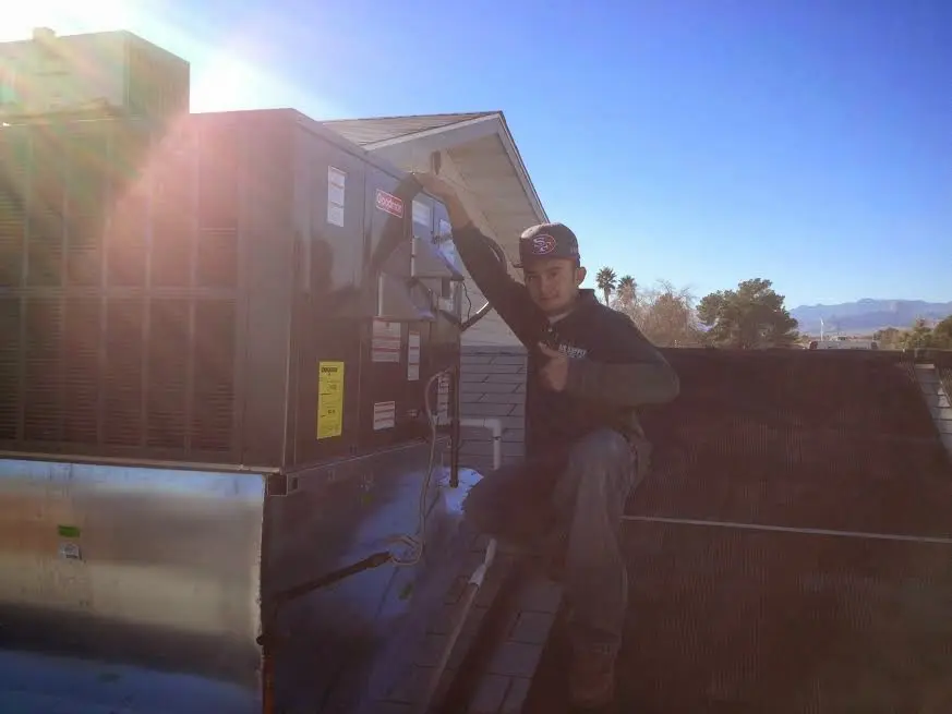 HVAC technician performing AC Tune-Up on a rooftop unit in Woodmere